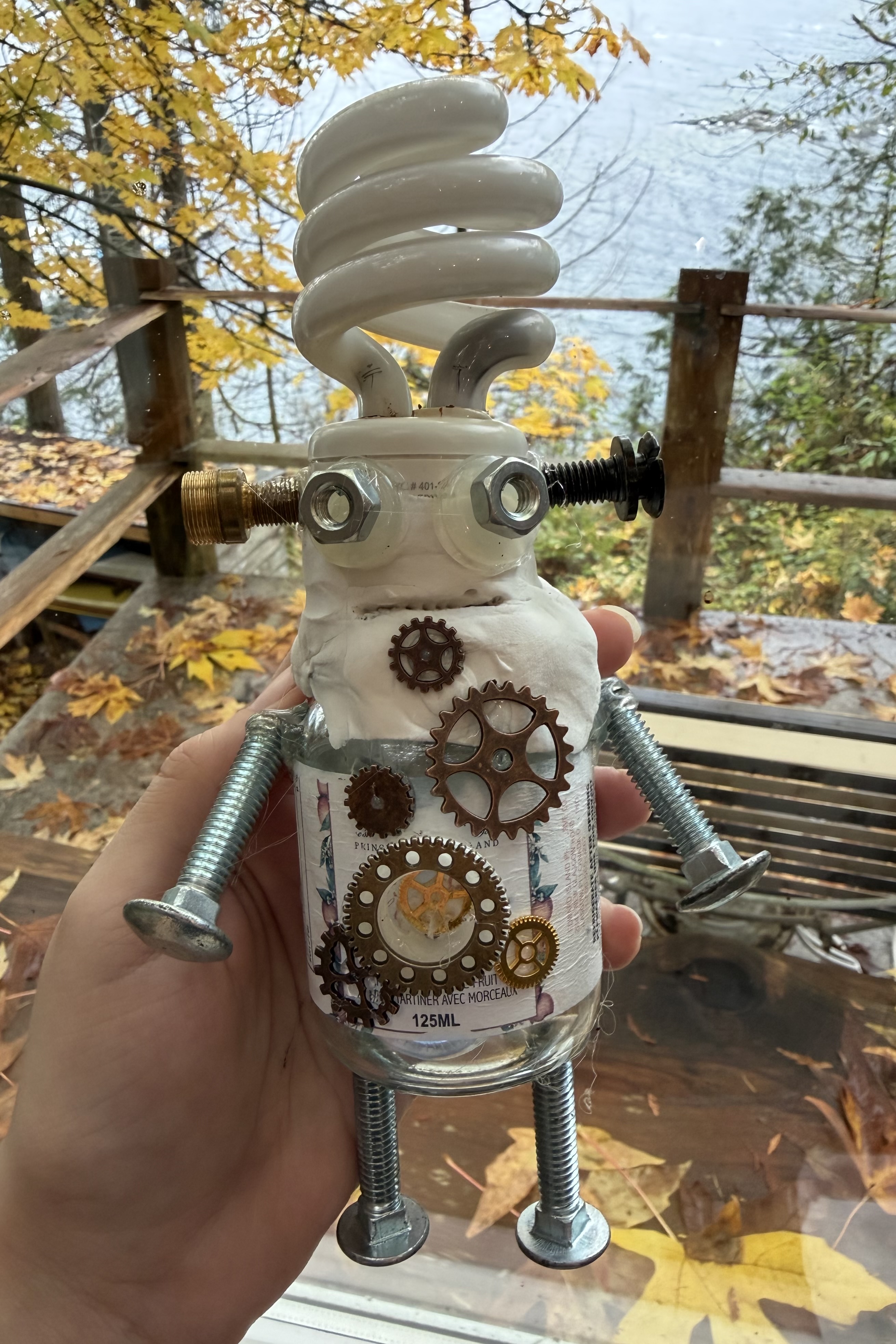 Handmade found-object robot example with gears, wire, and a spiral bulb head.